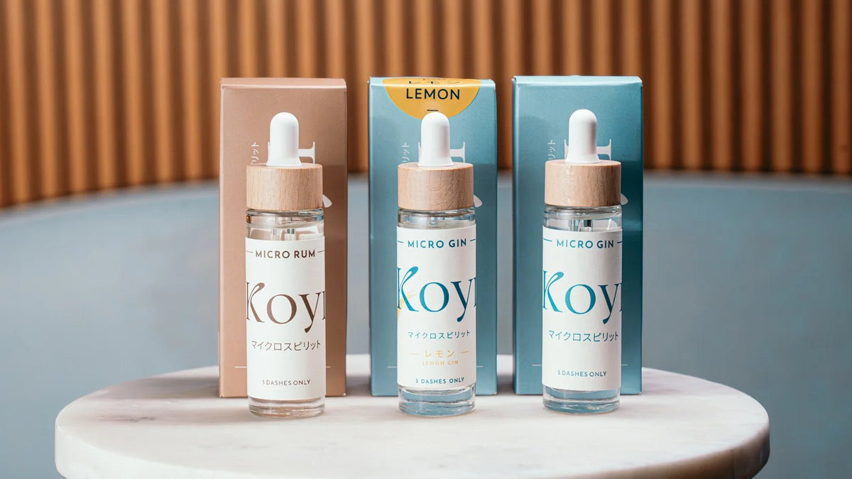 Drei KOYI Micro Spirits Flaschen mit Faltschachteln auf einem Marmortisch
