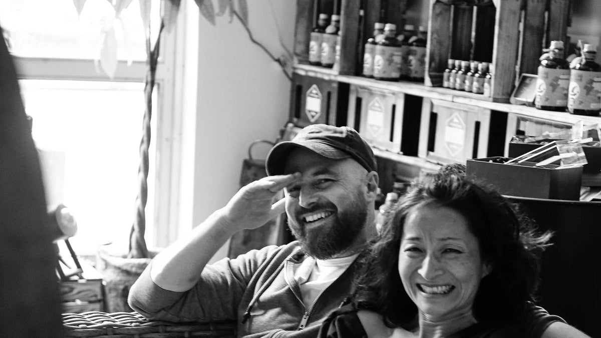 Yuka Suzuki und Dr. Hauke Günther lachend auf einem Sofa, Schwarz-Weiß-Foto